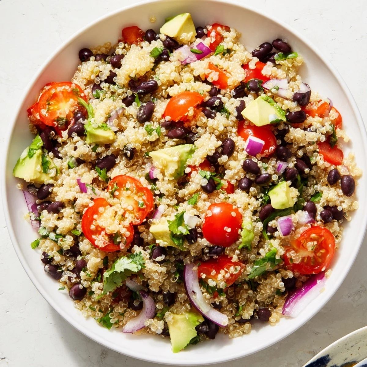 This Quinoa Black Bean Salad boasts vibrant tomatoes and creamy avocado, ready to eat!