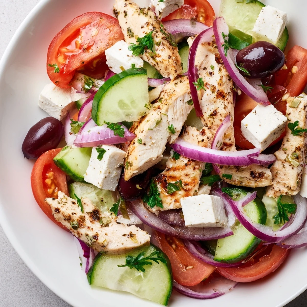 Delicious Greek salad with grilled chicken: tender chicken atop fresh veggies and feta.