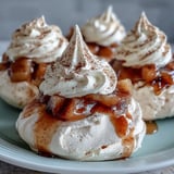 A single Mini Hot Toddy Pavlova showcases its crisp, chewy meringue nest filled with spiced pears and a cloud of vanilla cream.
