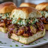 Juicy BBQ chicken sliders topped with tangy coleslaw, served on soft slider buns for a festive 4th of July meal.  