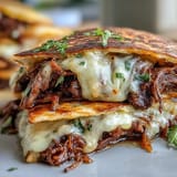 Cheesy birria quesadillas, perfect for dipping into savory consommé, served hot.
