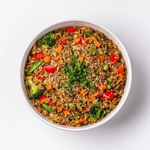 A steaming bowl of Crispy Vegetable Fried Rice showcases perfectly crisped rice with vibrant stir-fried vegetables and herbs.