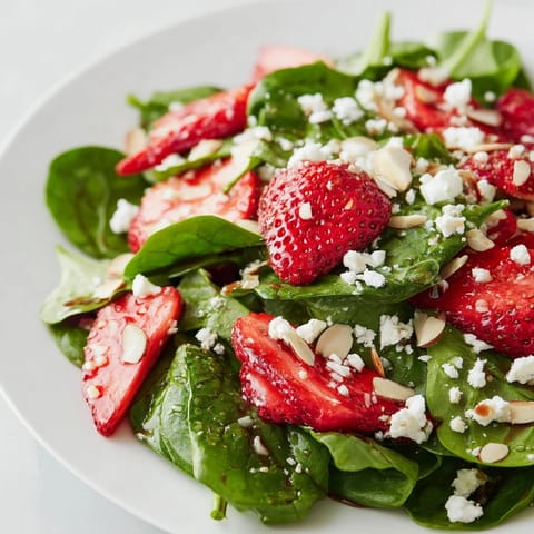 Bright, sweet strawberries and creamy feta topping a vibrant strawberry spinach salad dish.