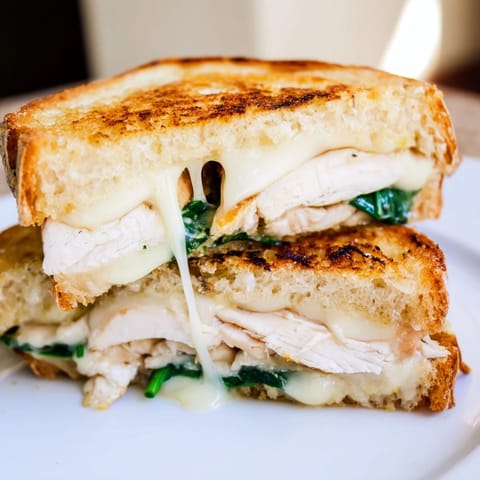 Juicy grilled chicken and fresh spinach peek out from inside the toasted sourdough, melted cheese pulling apart in a savory bite.