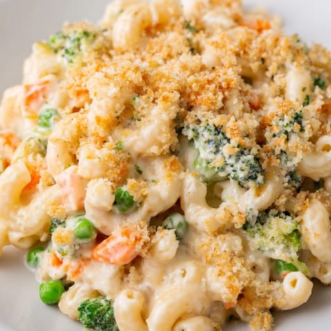 Steaming serving of homemade Garden Veg Mac and Cheese in a white ceramic dish, topped with crispy panko breadcrumbs next to a fresh green salad.  