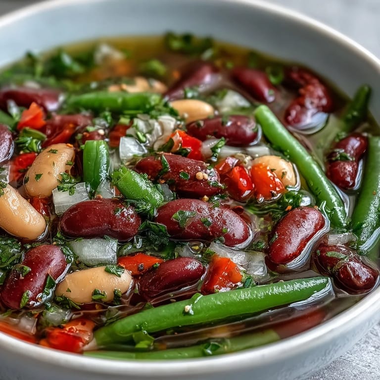 Three-Bean Salad Soup with tender beans and vegetables, steaming alongside crusty bread for a hearty, zesty lunch or dinner.